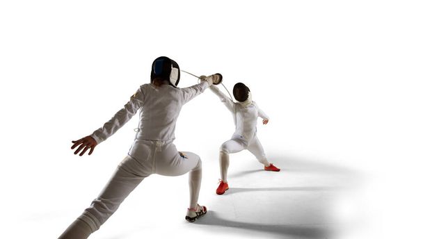 Two female fencing athletes fight isolated on white - Photo, Image