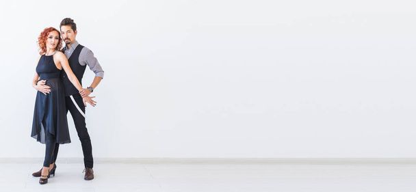 Социальный танец, бачата, кизомба, зук, концепция танго - Мужчина обнимает женщину, танцуя на белом фоне в студии
. - Фото, изображение