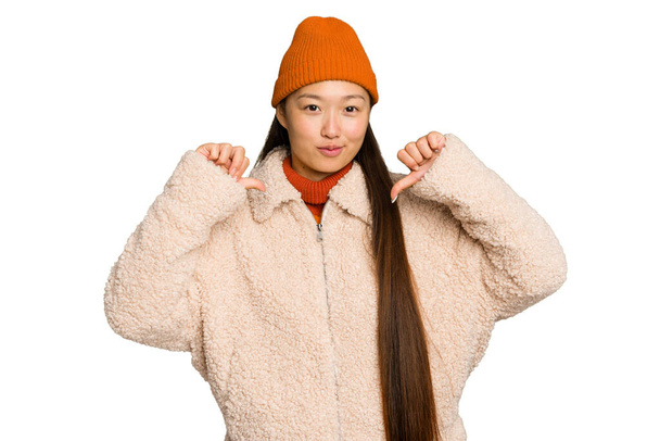 Молода азіатка в зимовому одязі ізольована на фоні зеленого хрому відчуває себе гордою і впевненою в собі, наприклад, слідувати
. - Фото, зображення