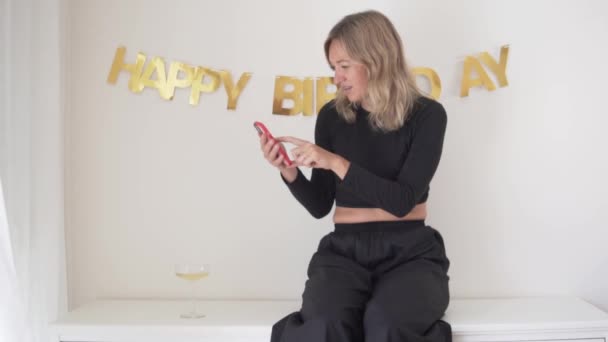 Μια όμορφη γυναίκα γιορτάζει τα γενέθλιά της και μόνο, δέχεται συγχαρητήρια μέσω βίντεο επικοινωνίας από το τηλέφωνο. - Πλάνα, βίντεο
