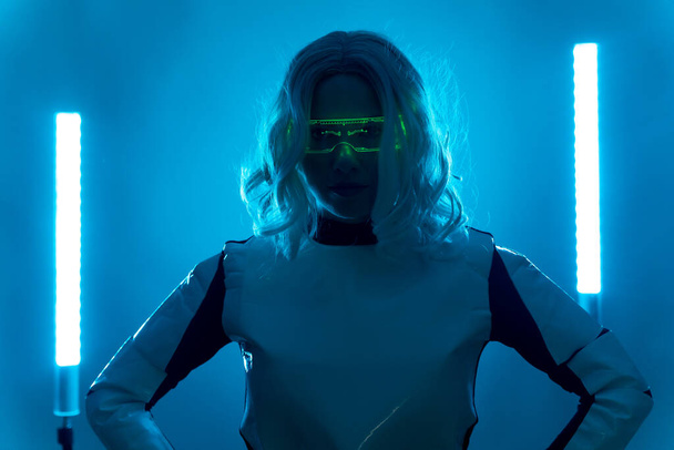 Futuristic concept, silhouette of a young woman with glasses from the future on a blue background - 写真・画像