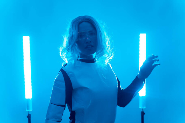 Young woman in futuristic suit and glasses with blue led lights, virtual or metaverse concept - Valokuva, kuva