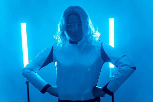 A woman in a futuristic suit and glasses with blue lights, virtual or metaverse concept, looking at the camera - Photo, image