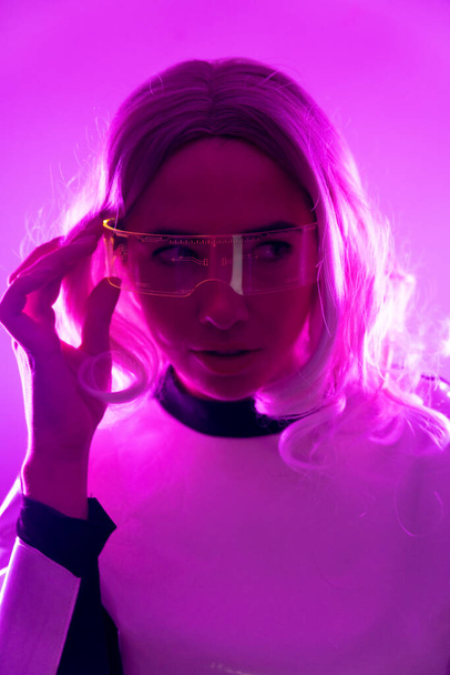 A woman in futuristic suit and glasses with pink lights, virtual or metaverse concept, vertical photo - Photo, image