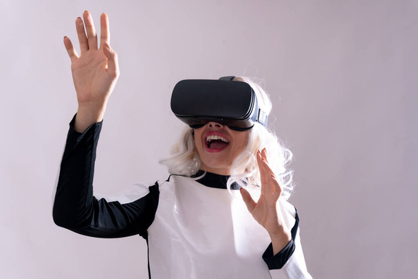 Woman with virtual reality glasses, futuristic concept, metaverse surprised with the virtual world and with her mouth open - Photo, Image