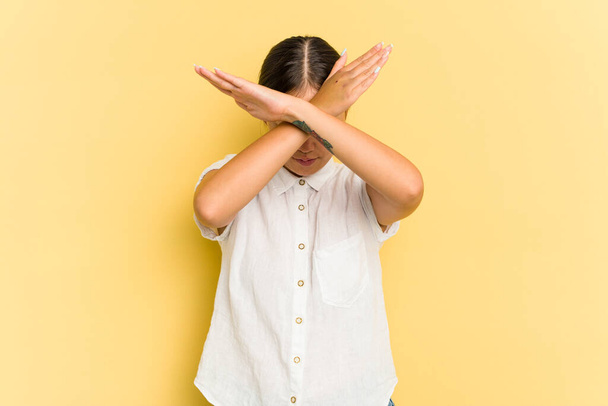 Young Asian woman isolated on yellow background keeping two arms crossed, denial concept. - Photo, Image