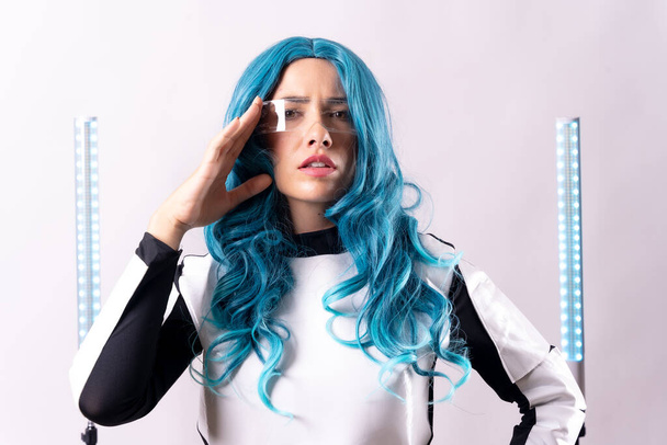 Futuristic, portrait of a young woman with blue hair, wearing augmented reality glasses looking at the camera - Photo, Image