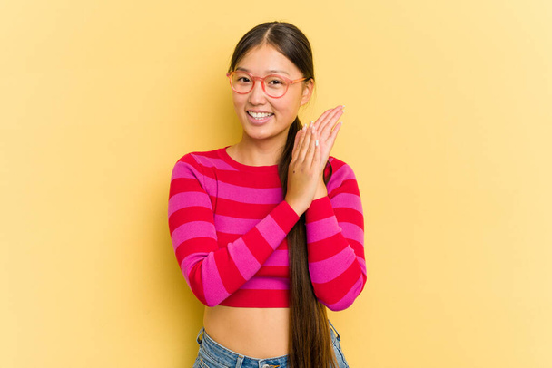 Jeune femme asiatique isolée sur fond jaune se sentant énergique et confortable, les mains frottées confiantes. - Photo, image