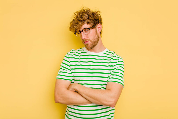 Young caucasian man isolated on yellow background who is bored, fatigued and need a relax day. - Фото, зображення