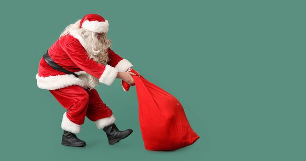 Санта Клаус з важкою сумкою на зеленому тлі з простором для тексту - Фото, зображення
