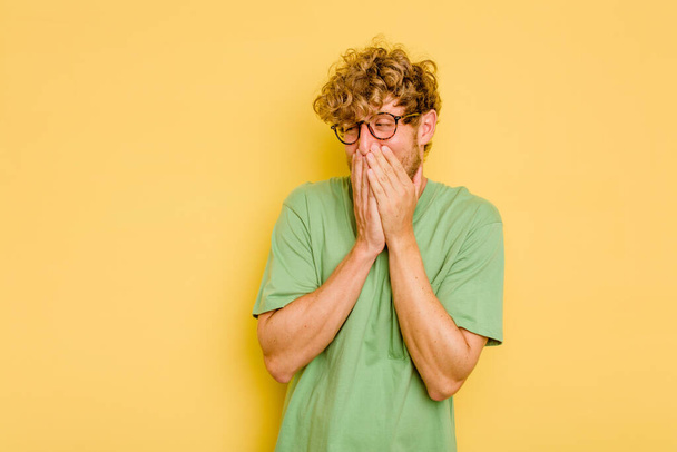 Young caucasian man isolated on yellow background laughing about something, covering mouth with hands. - Photo, Image