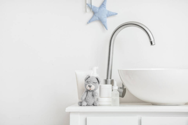 Fregadero moderno, juguete lindo y accesorios de baño para niños cerca de la pared blanca - Foto, imagen