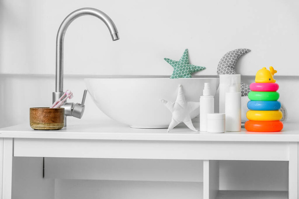 Different bath accessories for children and toys near modern sink on table - Фото, изображение