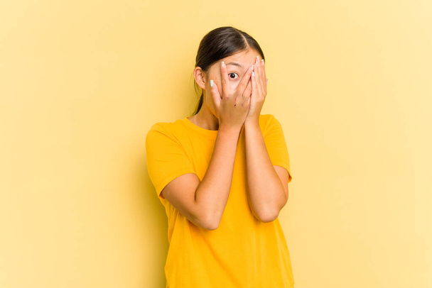 Young Asian woman isolated on yellow background blink through fingers frightened and nervous. - Φωτογραφία, εικόνα