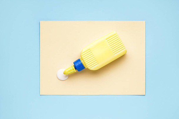 Bottle of glue with paper sheet on blue background - Photo, Image
