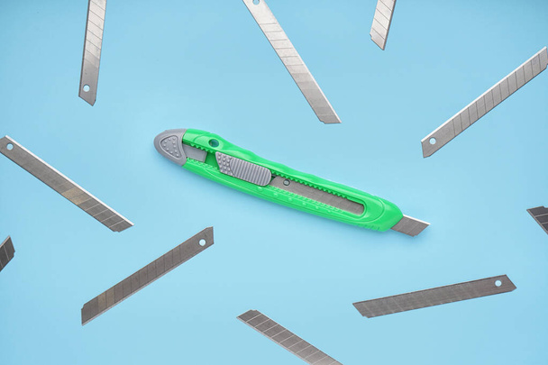 Zielony nóż użytkowy z ostrzami na niebieskim tle - Zdjęcie, obraz