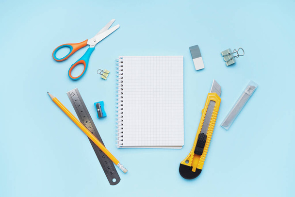 Utility knife with stationery on blue background - 写真・画像
