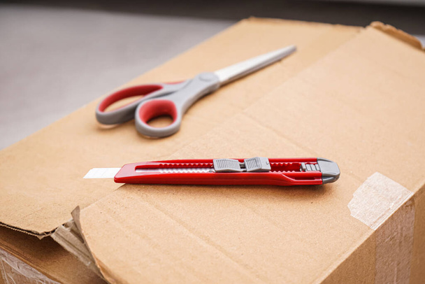 Cuchillo utilitario con tijeras en caja de cartón, primer plano - Foto, Imagen