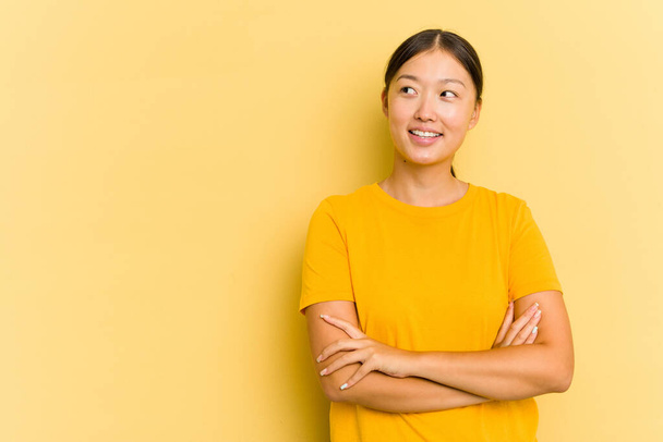 Young Asian woman isolated on yellow background smiling confident with crossed arms. - Photo, Image