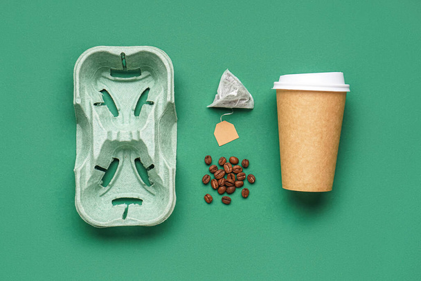 Composition with holder, paper cup, coffee beans and tea bag on color background - Photo, Image