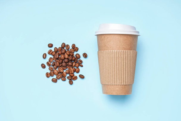 Paper cup and coffee beans on color background - Photo, Image