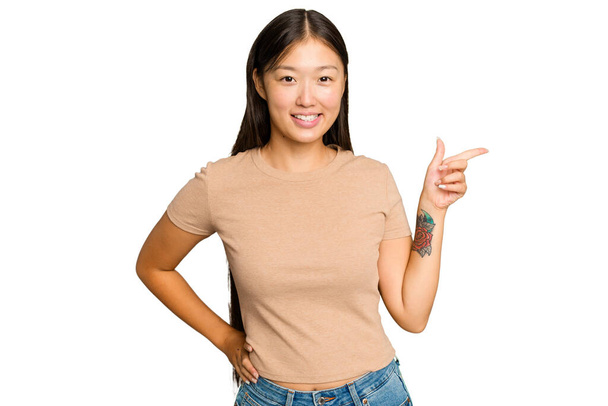 Giovane donna asiatica isolata su sfondo cromatico verde sorridente allegramente indicando con indice di distanza. - Foto, immagini