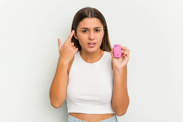 Young indian woman holding an electronic pink car keys showing a disappointment gesture with forefinger. - Фото, зображення