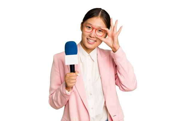Young TV Asian presenter isolated on green chroma background excited keeping ok gesture on eye. - Fotó, kép