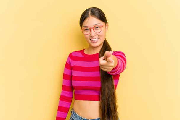 Young Asian woman isolated on yellow background cheerful smiles pointing to front. - Foto, Imagem