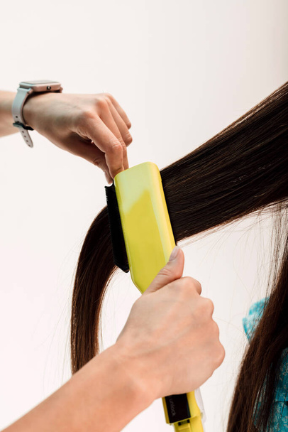 Mãos de um cabeleireiro profissional. O mestre uniformiza o cabelo dos clientes com um curler. Foto de alta qualidade - Foto, Imagem