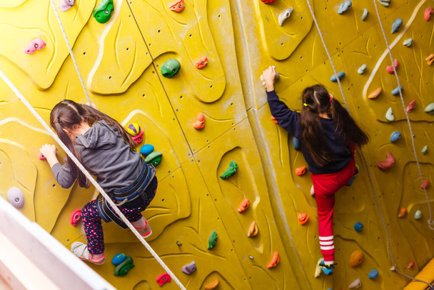 Two little girls climbing a rock wall - 写真・画像