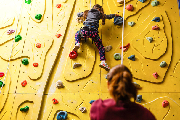 Little girl climbing a rock wall indoor - Фото, изображение