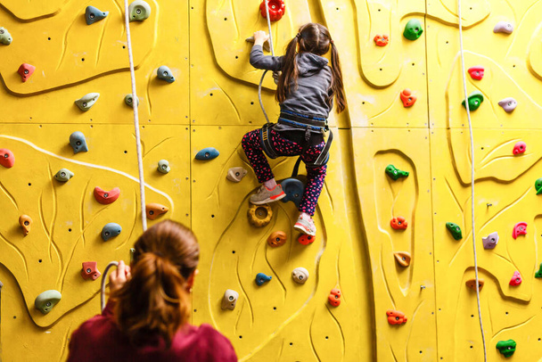Little girl climbing a rock wall indoor - Foto, imagen