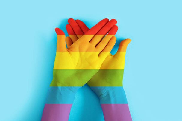 Mains féminines peintes aux couleurs du drapeau LGBT sur fond bleu. Contexte de tolérance LGBT, concept de fierté - Photo, image