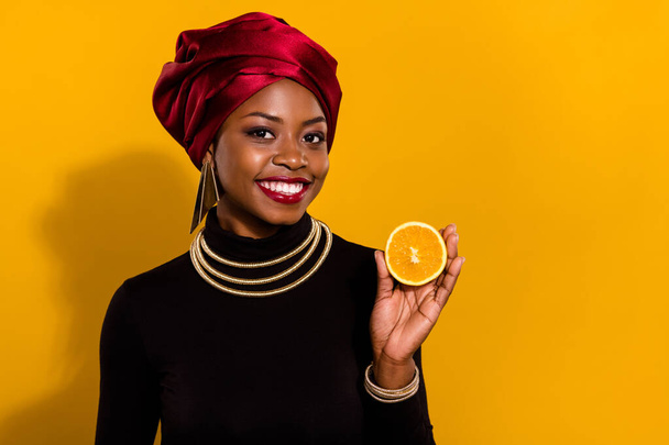 Portret dziewczyny z dodatnim uchwytem pokazuje pół pomarańczowy cytrusowe witamina c izolowane na żółtym tle. - Zdjęcie, obraz