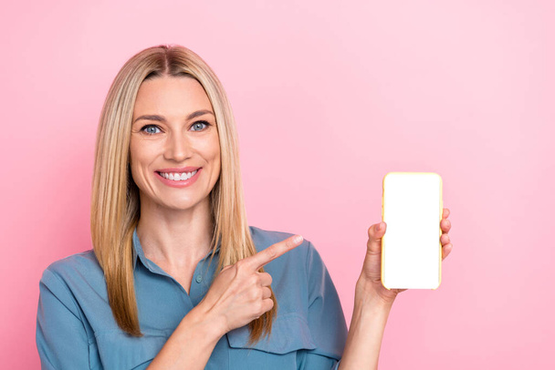 Photo of charming attractive adorable woman blond hair indicating at phone touchscreen recommend app isolated on pink color background. - Zdjęcie, obraz
