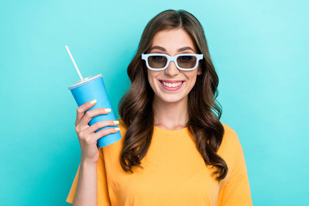 Closeup photo of young pretty nice toothy smile girl wear t-shirt hold cup soda good mood wear eyeglasses film movie isolated on cyan color background. - Foto, Imagem