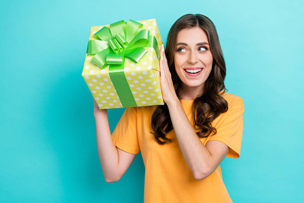 Photo of young attractive gorgeous pretty lady curly hair wear orange t-shirt excited look her new surprise gift birthday good mood isolated on cyan color background. - 写真・画像