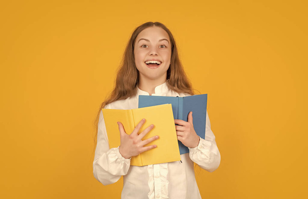 happy teen girl hold school workbook on yellow background, school. - Foto, imagen