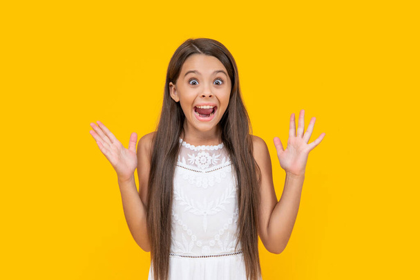 surprised teen kid in white dress has long hair on yellow background. - Фото, изображение