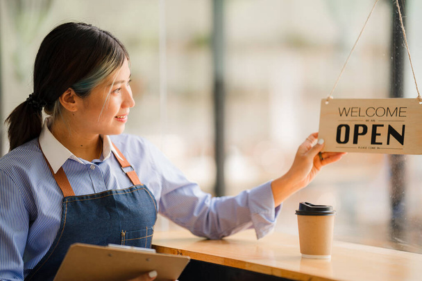 Ázsiai nők felállítottak egy táblát, hogy nyissanak egy boltot, hogy üdvözöljék a vásárlókat egy kávézóban. kisvállalkozás tulajdonosa és startupok és kávézók élelmiszer és ital koncepció - Fotó, kép