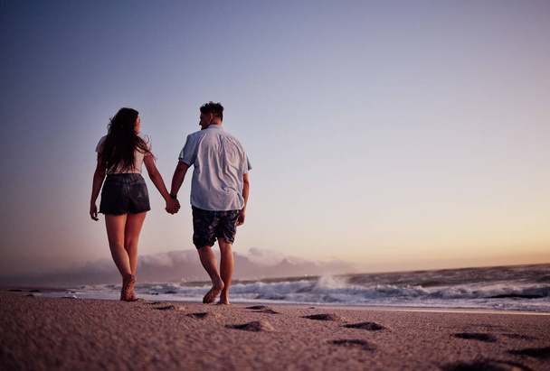 Couple, holding hands and love for beach walk together in romantic summer sunset in the outdoors. Hand hold of man and woman walking on a beautiful ocean coast in romance for vacation in Costa Rica. - Foto, imagen
