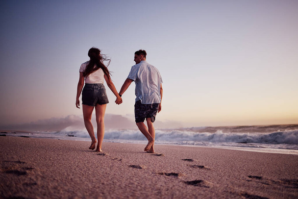 Love, holding hands and couple walking on the beach relax, bond and enjoy romantic quality time together in Israel. Peace, freedom and ocean air for man and woman on sea sand travel for wellness calm. - Fotografie, Obrázek