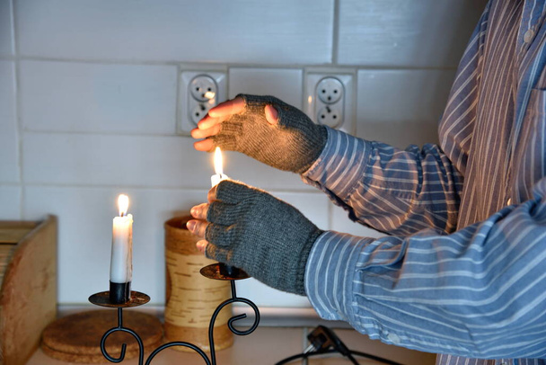 Symbols of poverty: man at home without electricity, without heating. Using candles to warm up. - Photo, Image