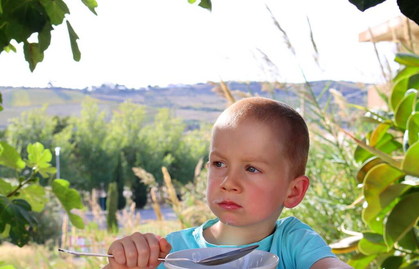 Ein kurzhaariger, blonder Junge mit einem zweifelnden Blick im Gesicht. Ein vorsichtiger fünfjähriger Junge.  - Foto, Bild