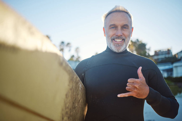 Playa, tabla de surf y un viejo surfista feliz hombre con signo de mano y sonrisa. Libertad, deportes acuáticos y felicidad, diversión en vacaciones de jubilación en Australia. Salud, fitness y senior listos para surfear - Foto, Imagen