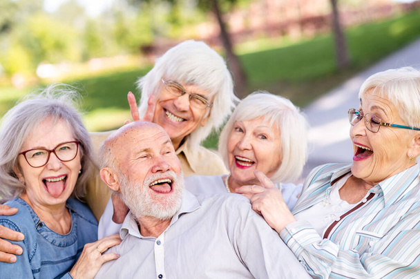 Group of happy elderly people bonding outdoors at the park - Old people in the age of 60, 70, 80 having fun and spending time together, concepts about elderly, seniority and wellness aging - Foto, imagen