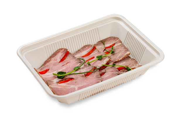 Bacon strips with peppers and herbs.  In a plastic container. Food to go. On a light background. - Foto, Imagen