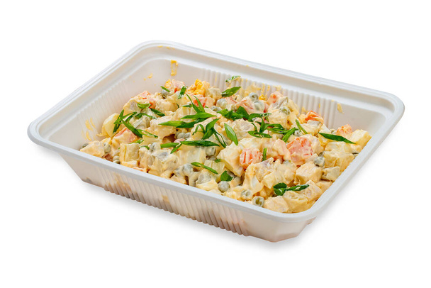 Traditional Russian salad "Olivier". In a plastic container. Food to go. On a light background. - Photo, image