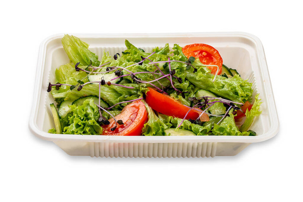 Salad with fresh vegetables and microgreens. In a plastic container. Food to go. On a light background. - Photo, image